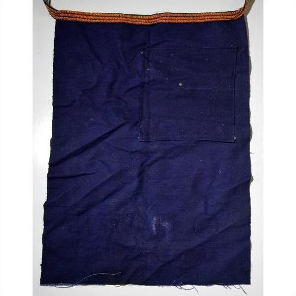 Dark blue wax-printed cotton apron with front pocket and striped orange-brown strap, close-up view.