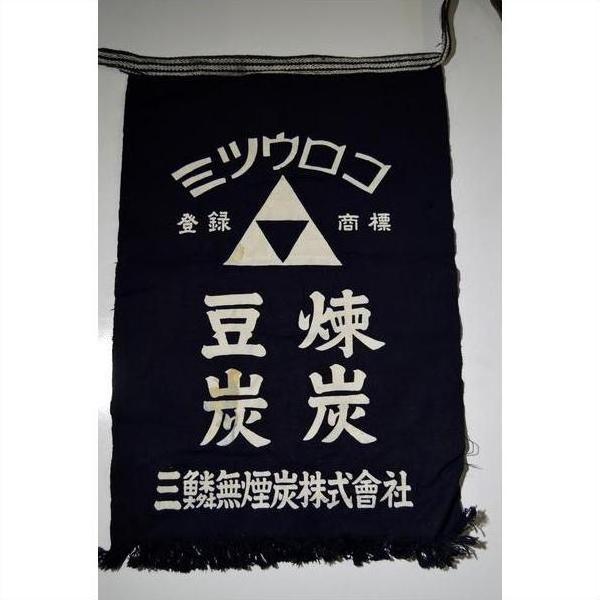 Navy cotton Taisho-era Japanese apron with white text, triangle logo, and fringe, close-up view.