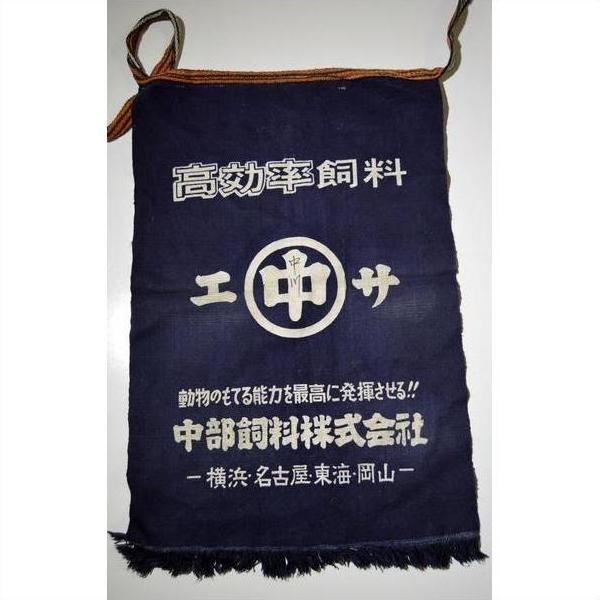 Blue wax-printed fabric Japanese apron with white logo, Japanese text, rope handle, and frayed edge, close-up.