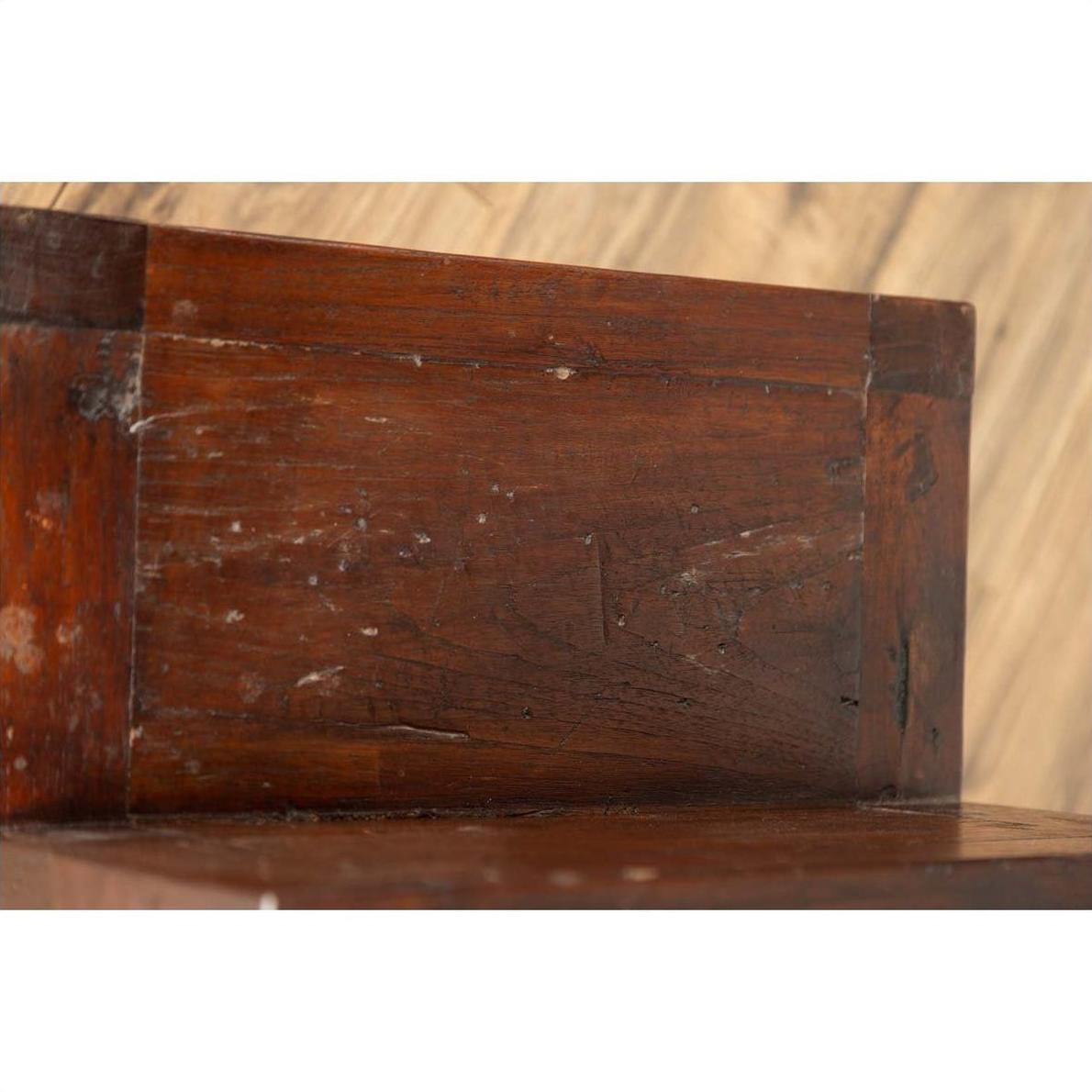 Close-up of brown wood staircase tansu cabinet with four drawers, Japanese style, set against wood paneling indoors.