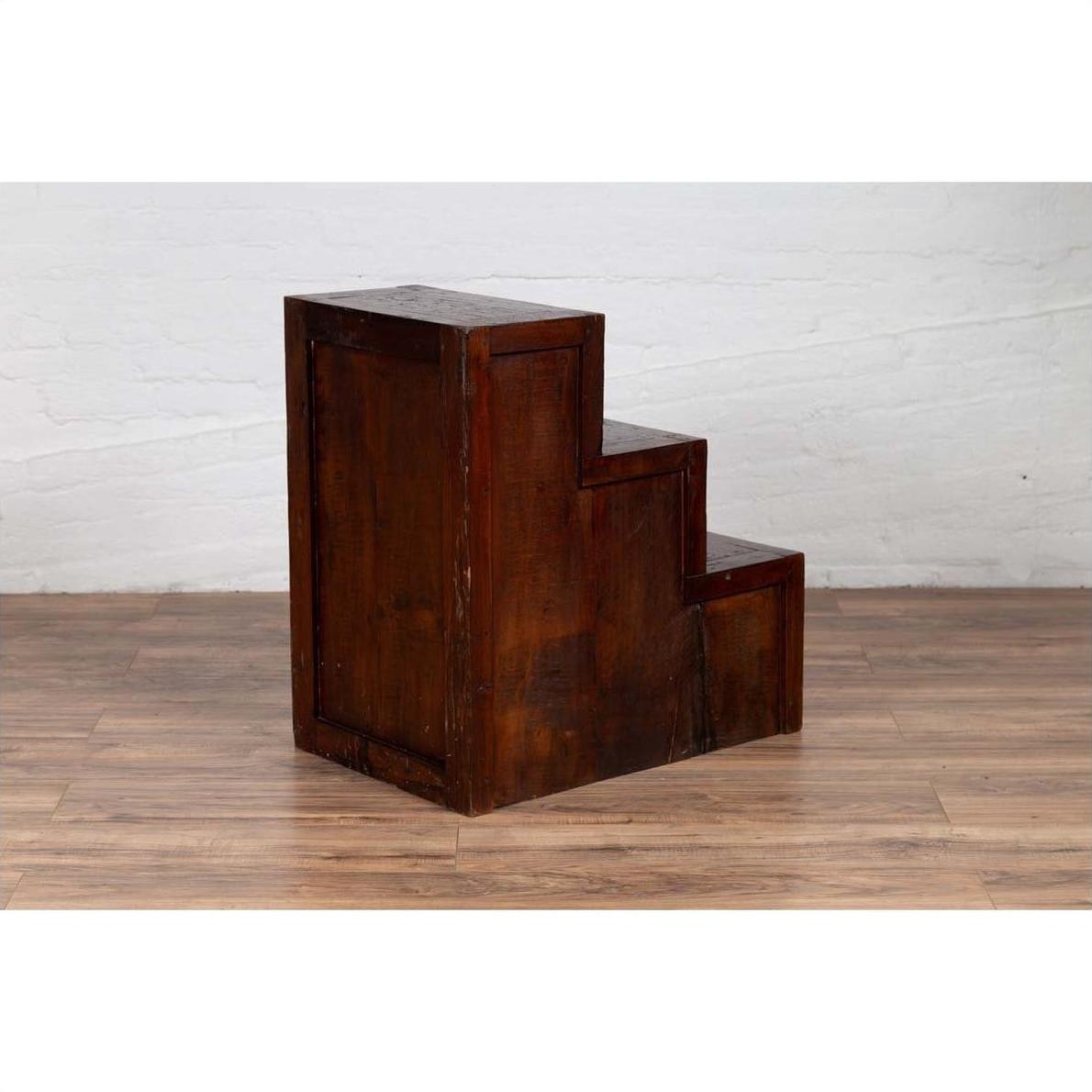 Brown wooden staircase tansu cabinet with four drawers, Japanese style, indoor setting.