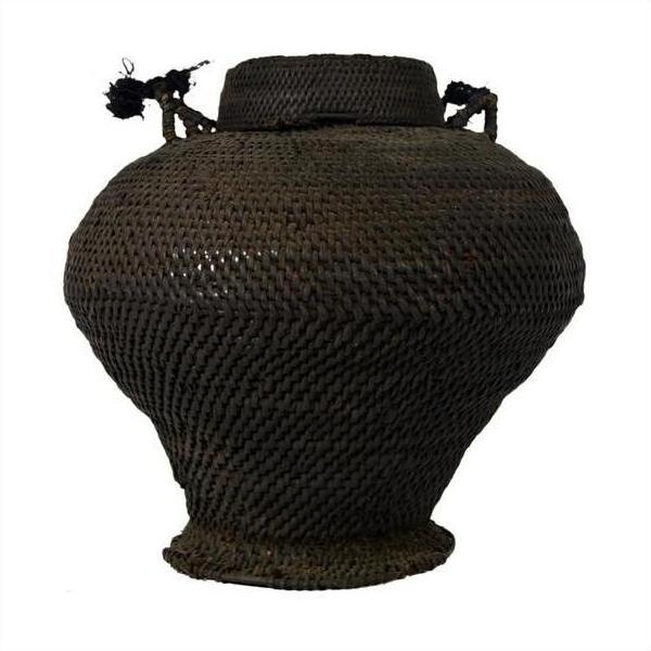 Close-up of large dark brown woven basket from the Philippines with wide body, narrow base, and top handles.