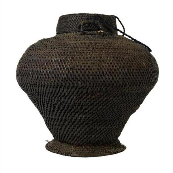 Close-up of dark brown rattan woven farmer's basket from the Philippines with a wide bottom, narrow neck, black string near top.