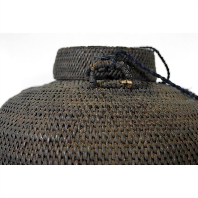 Close-up of a brown woven farmer's basket from the Philippines with handle and dark cord, on white background.
