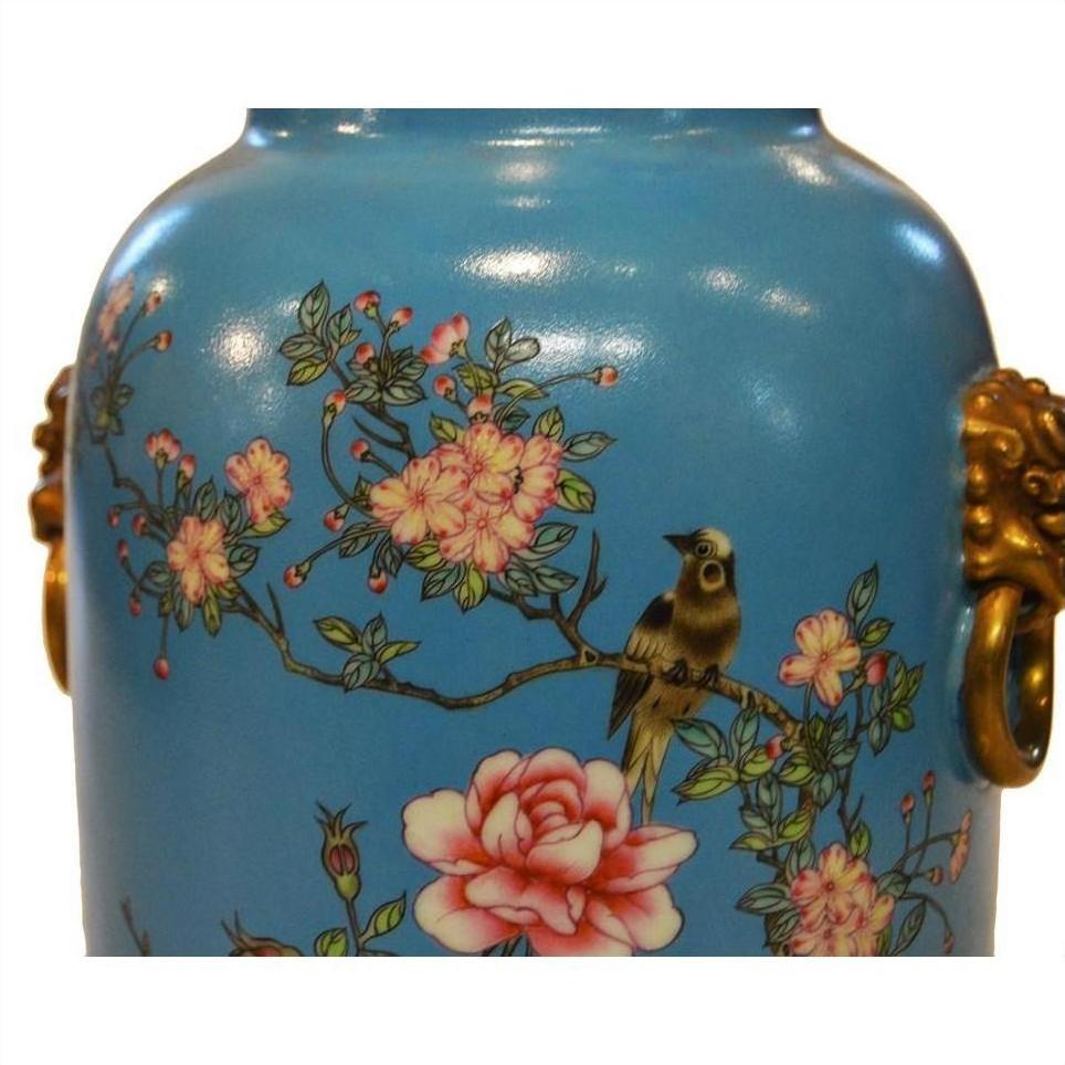 White porcelain vase with gold side handles, hand painted pink flowers, and bird on branch, close-up view.