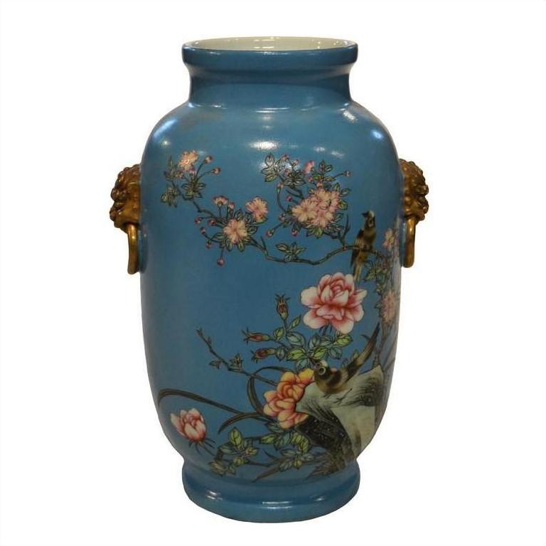 Close-up of vintage porcelain vase with hand painted flowers, birds, gold lion head handles, and glossy finish.
