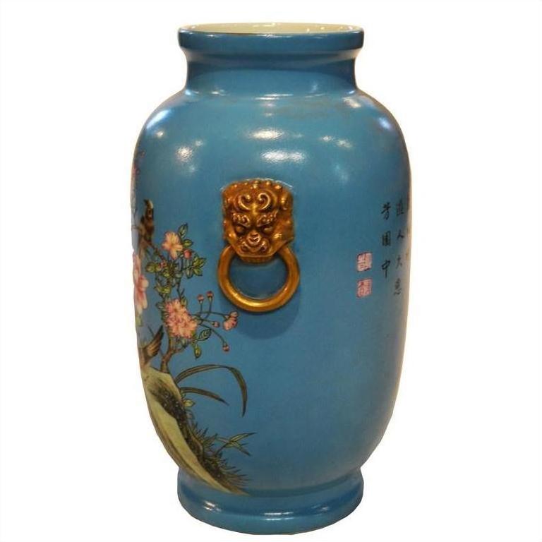 White porcelain vase with hand-painted flowers, birds, gold lion ring handles, and Chinese calligraphy, close-up.