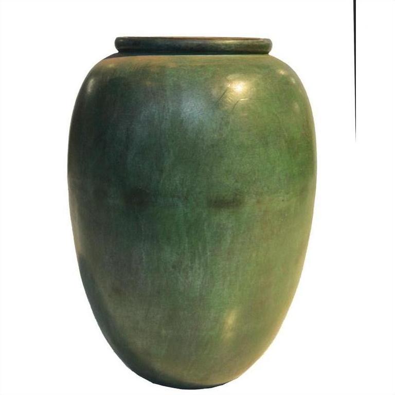 Close-up of vintage green bronze urn with large smooth body and narrow flared rim, used as subtle decor.