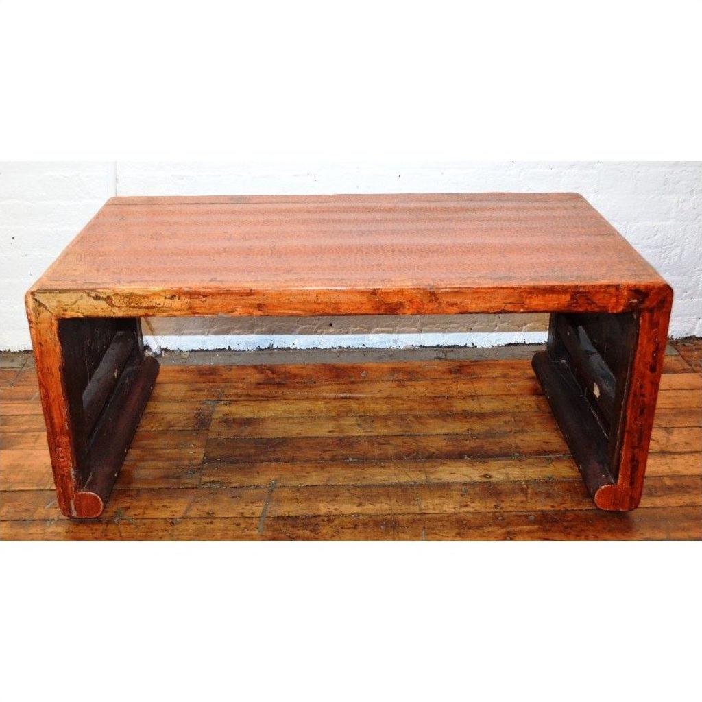 Rectangular lacquered waterfall table with thick legs on wooden floor, set against a white brick wall.