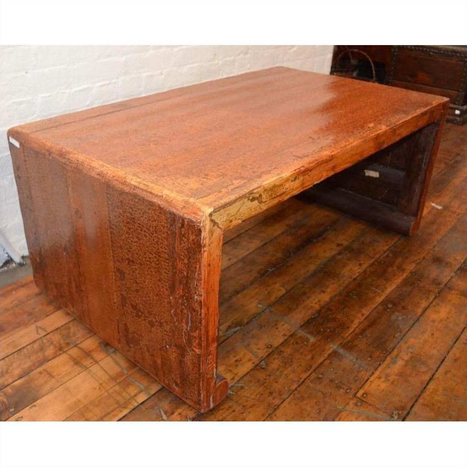 Large wood Waterfall Table with rectangular top on wooden floor beside white brick wall, wide angle view.