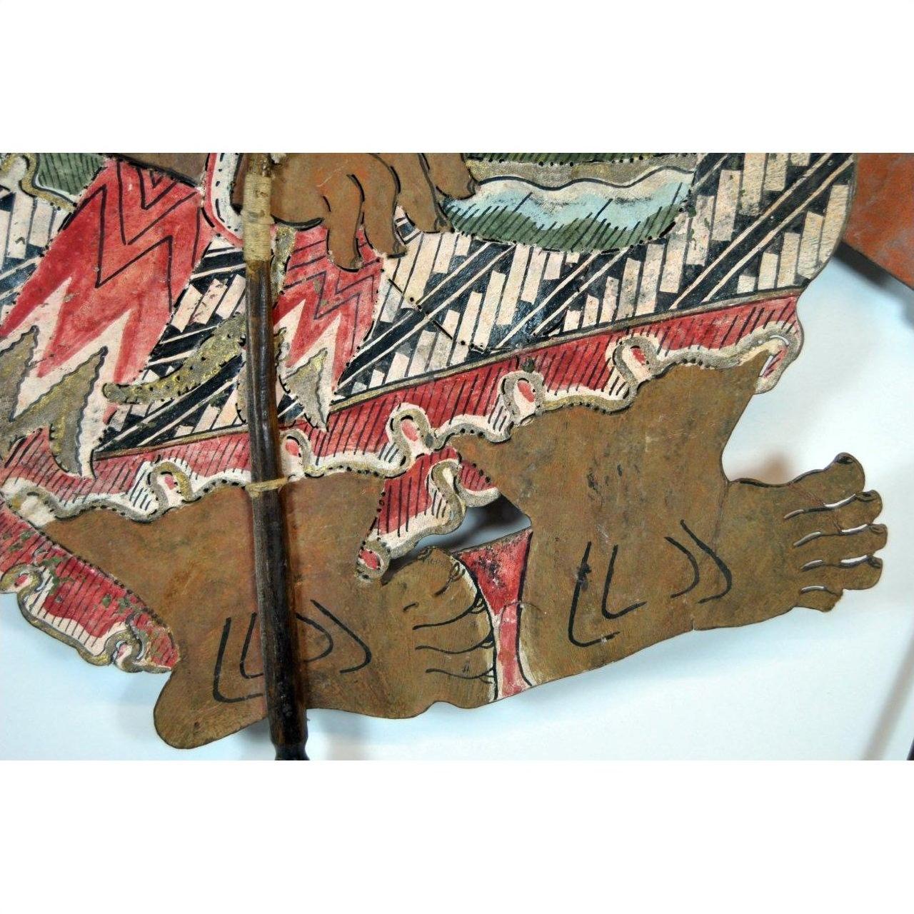 Close-up of colorful cowhide Wayang Kulit Balinese shadow puppet feet in a zigzag garment.