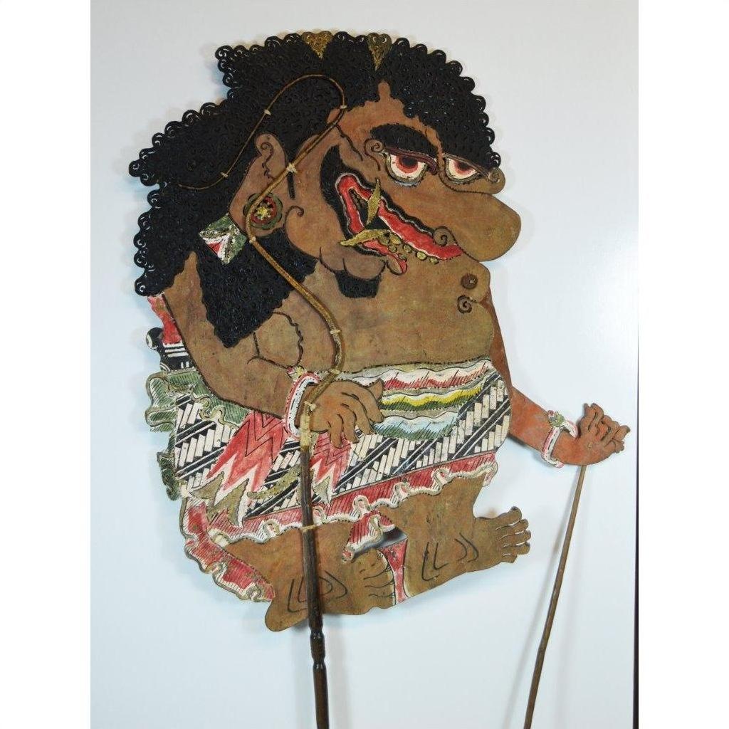 Close-up of antique Balinese Wayang Kulit shadow puppet, carved cowhide with bold features and ornate patterned attire.