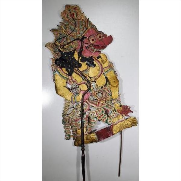 Close-up of red and yellow Wayang Kulit Balinese cowhide shadow puppet with intricate patterned clothing.