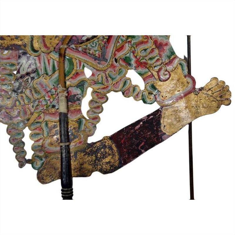 Close-up of colorful cowhide Wayang Kulit Balinese shadow puppet arm holding an intricately detailed staff.