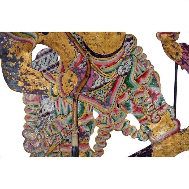White and gold cowhide Wayang Kulit Balinese shadow puppet with intricate patterns, close-up on white background.