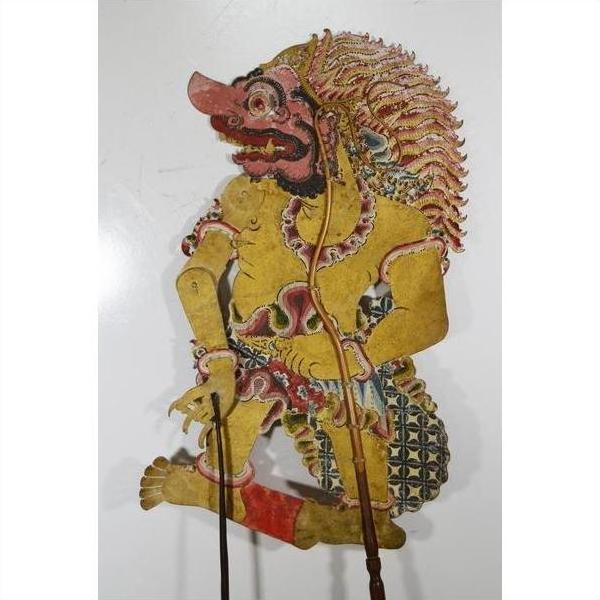 Yellow cowhide Wayang Kulit Balinese shadow puppet with ornate clothing and dramatic face, Indonesia, close-up.
