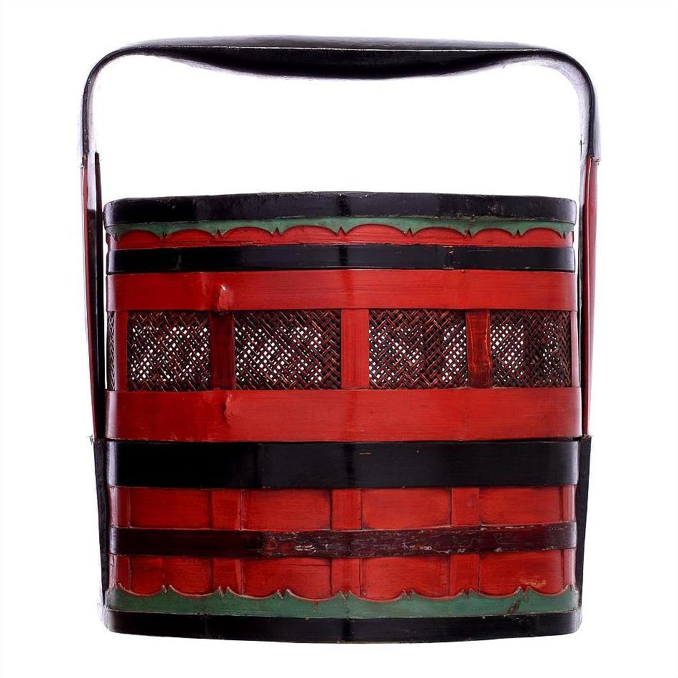Close-up of red and black wedding basket with green accents, black handle, and open side slats.