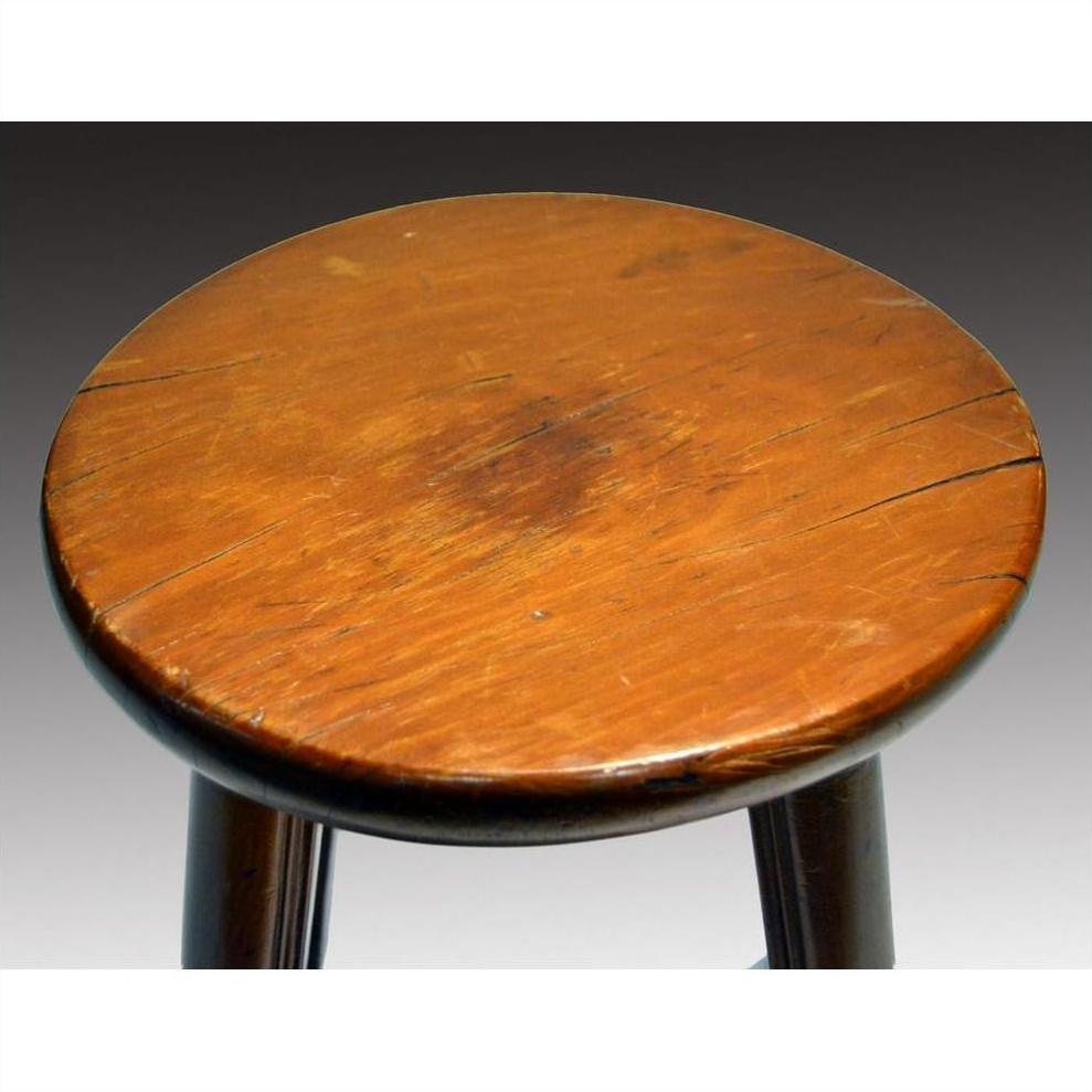 Close-up of a round brown wooden Antique Indonesian stool seat with rustic, scratched, and worn surface.