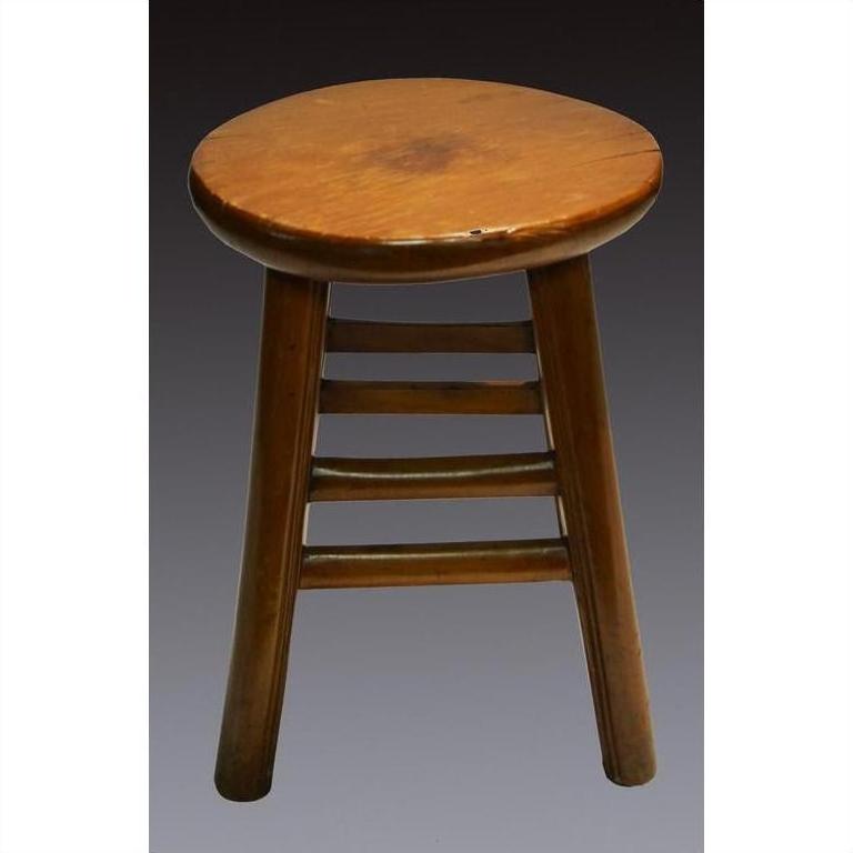 Brown wooden three-legged Indonesian stool with a round top and sturdy horizontal support bars, close-up view.