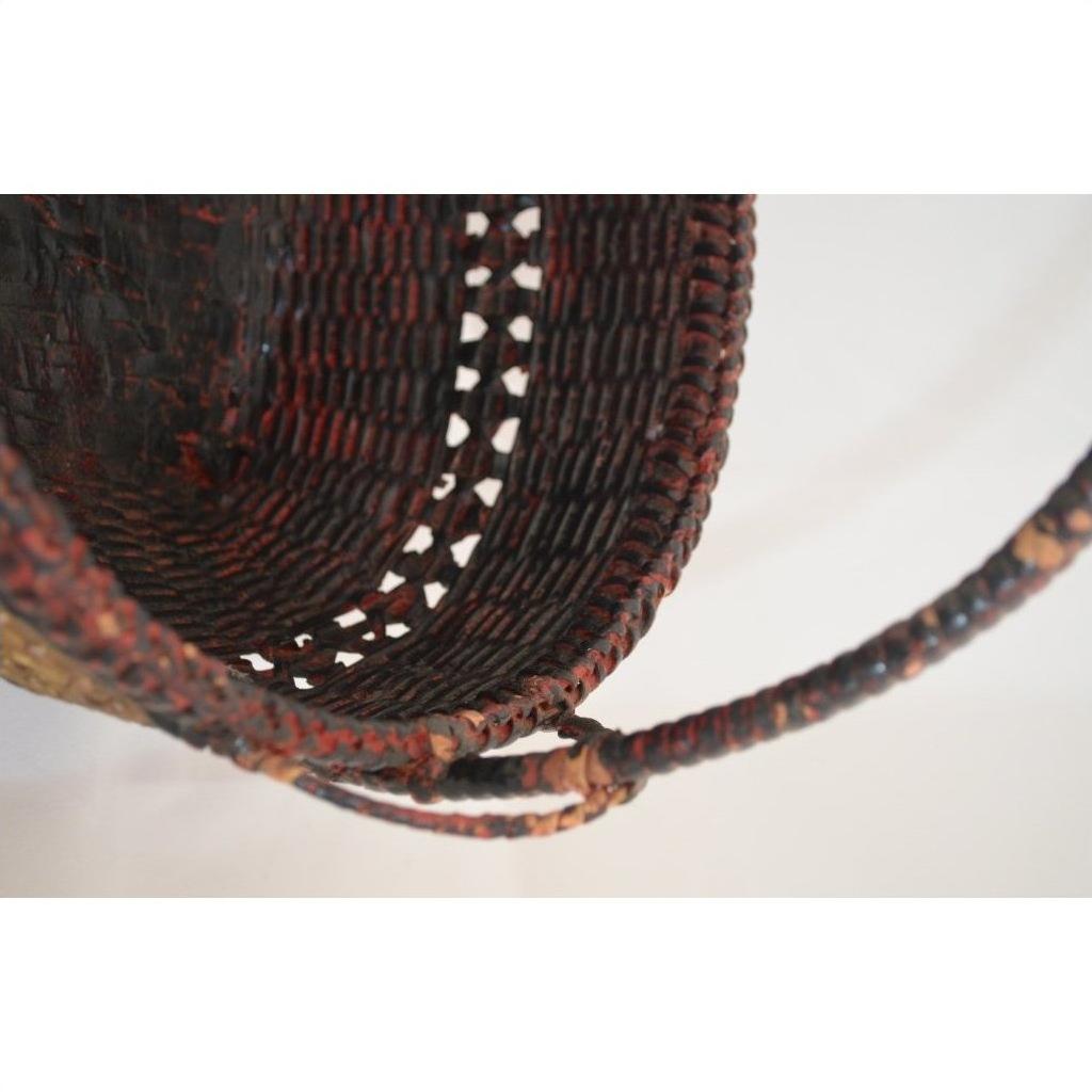 Close-up of natural bamboo offering basket with curved handle and intricate hand-woven texture and pattern.