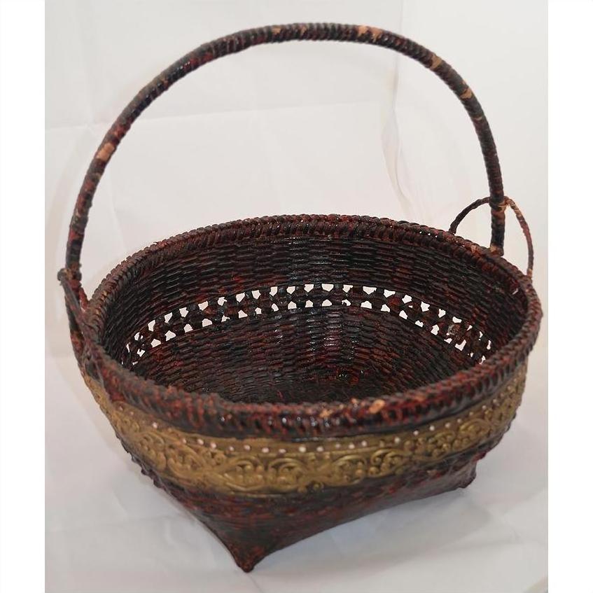 Red and gold woven bamboo offering basket with curved handle, close-up on white background.