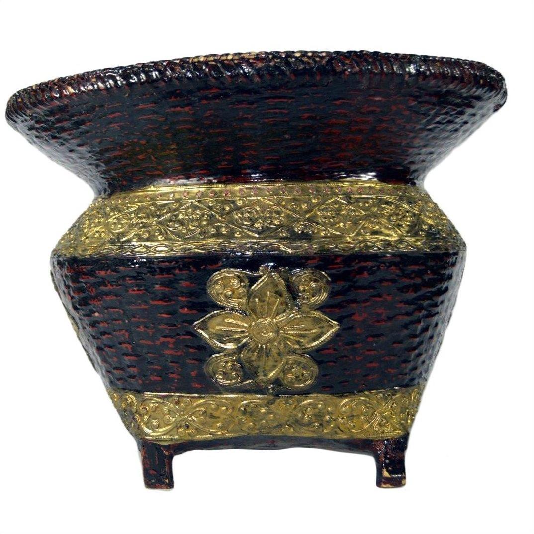 Black and gold woven bamboo offering basket with embossed floral design and four short legs, close-up.