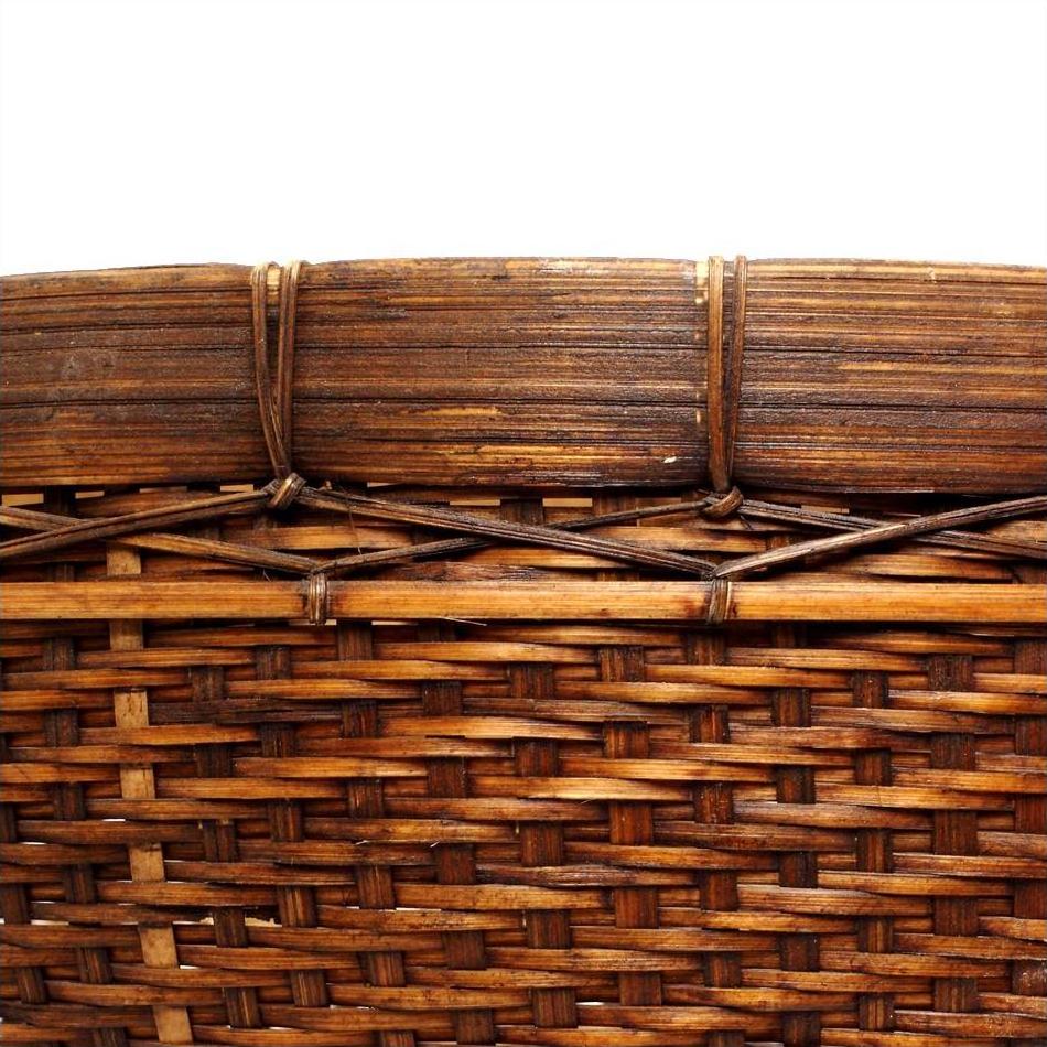 Close-up of a natural woven basket with intricate horizontal and diagonal patterns on a white background.