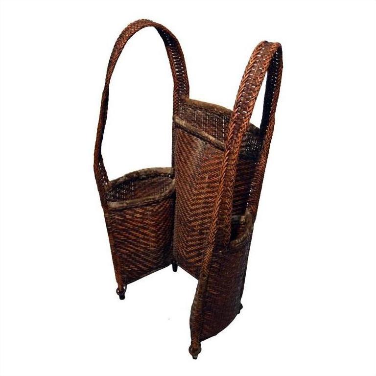 Natural rattan woven carrying basket with two tall handles and four small legs, close-up studio view.