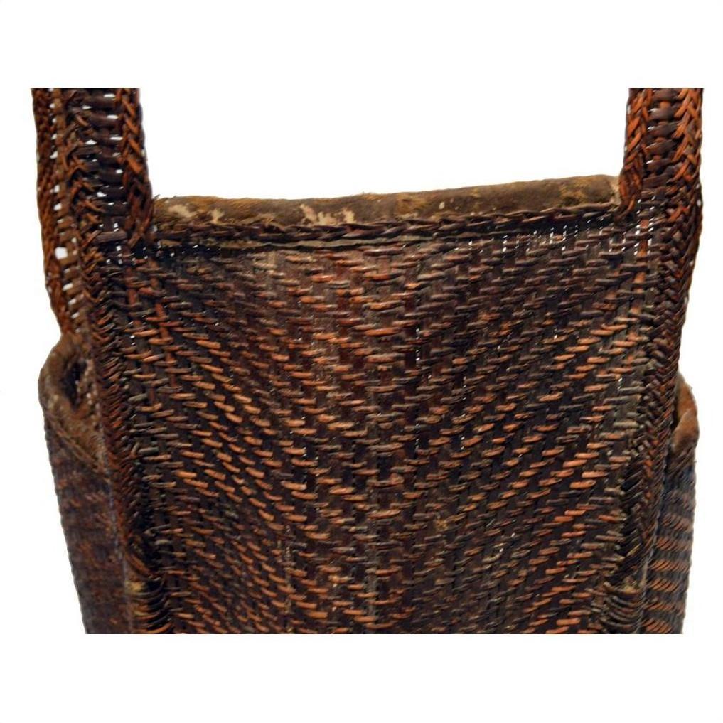 Close-up of natural rattan woven basket with sturdy handles and rustic texture against a white background.