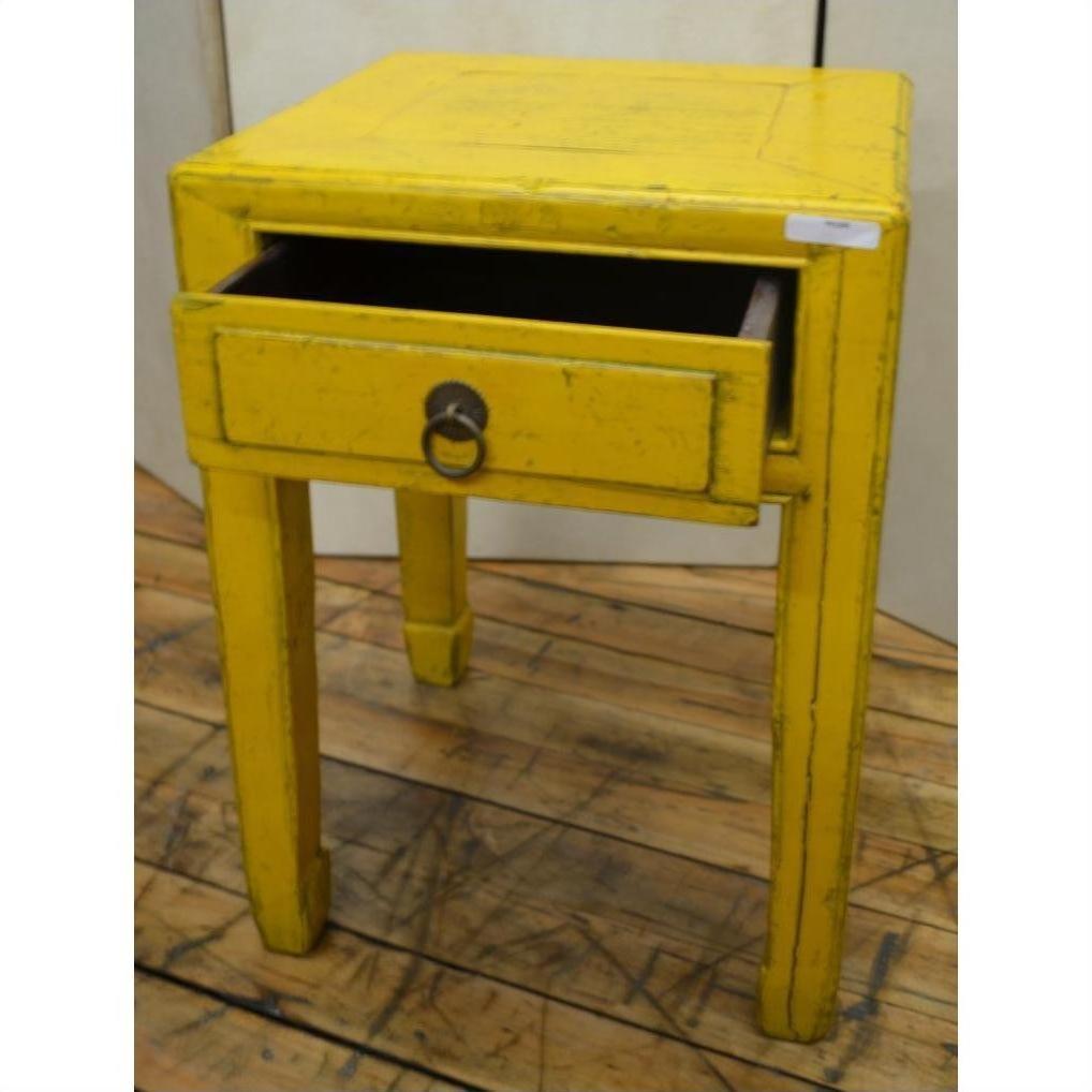 Yellow wood side table with a single drawer and horse hoof feet on a wooden floor.