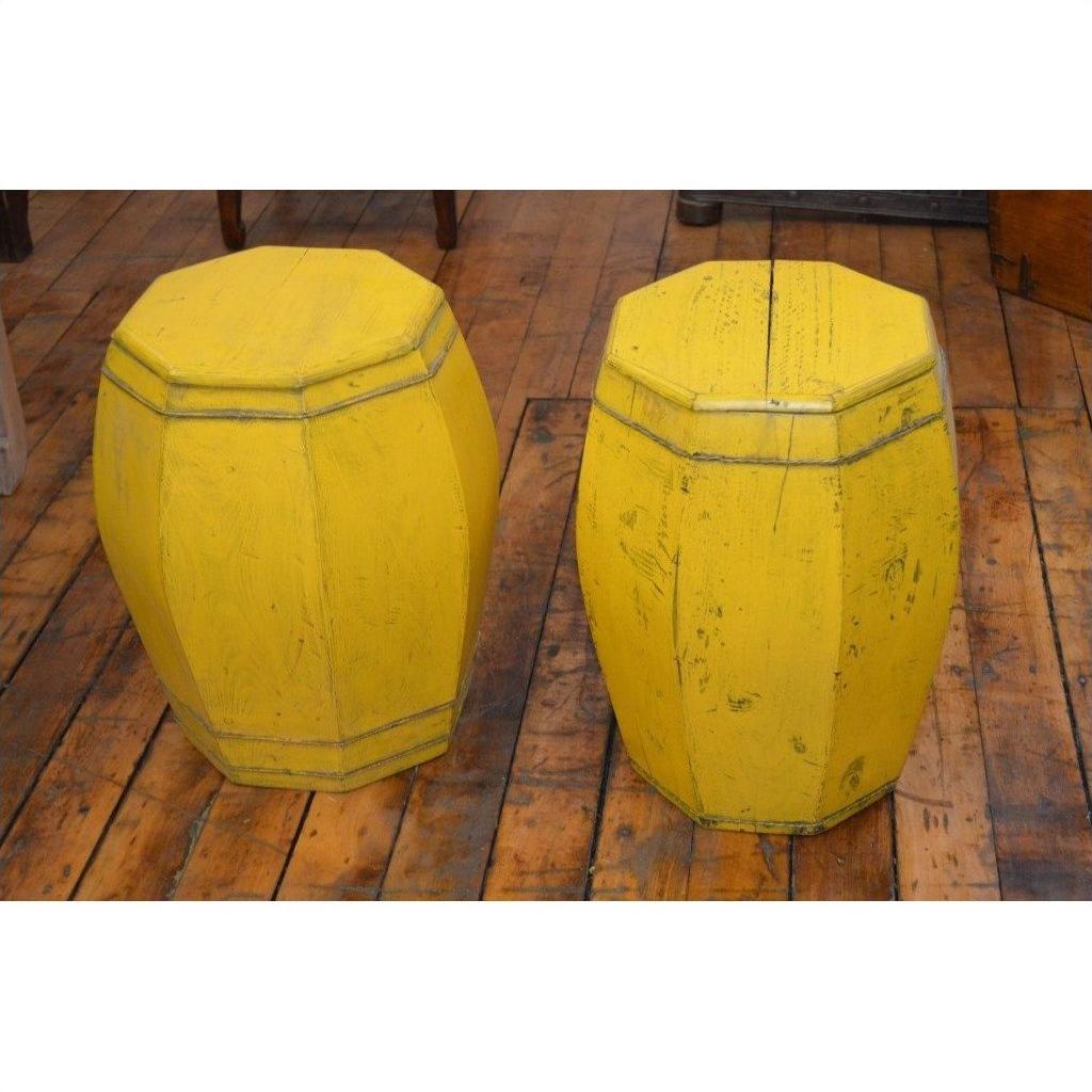 Yellow wooden side tables or drums on a worn wooden floor in a rustic indoor setting.